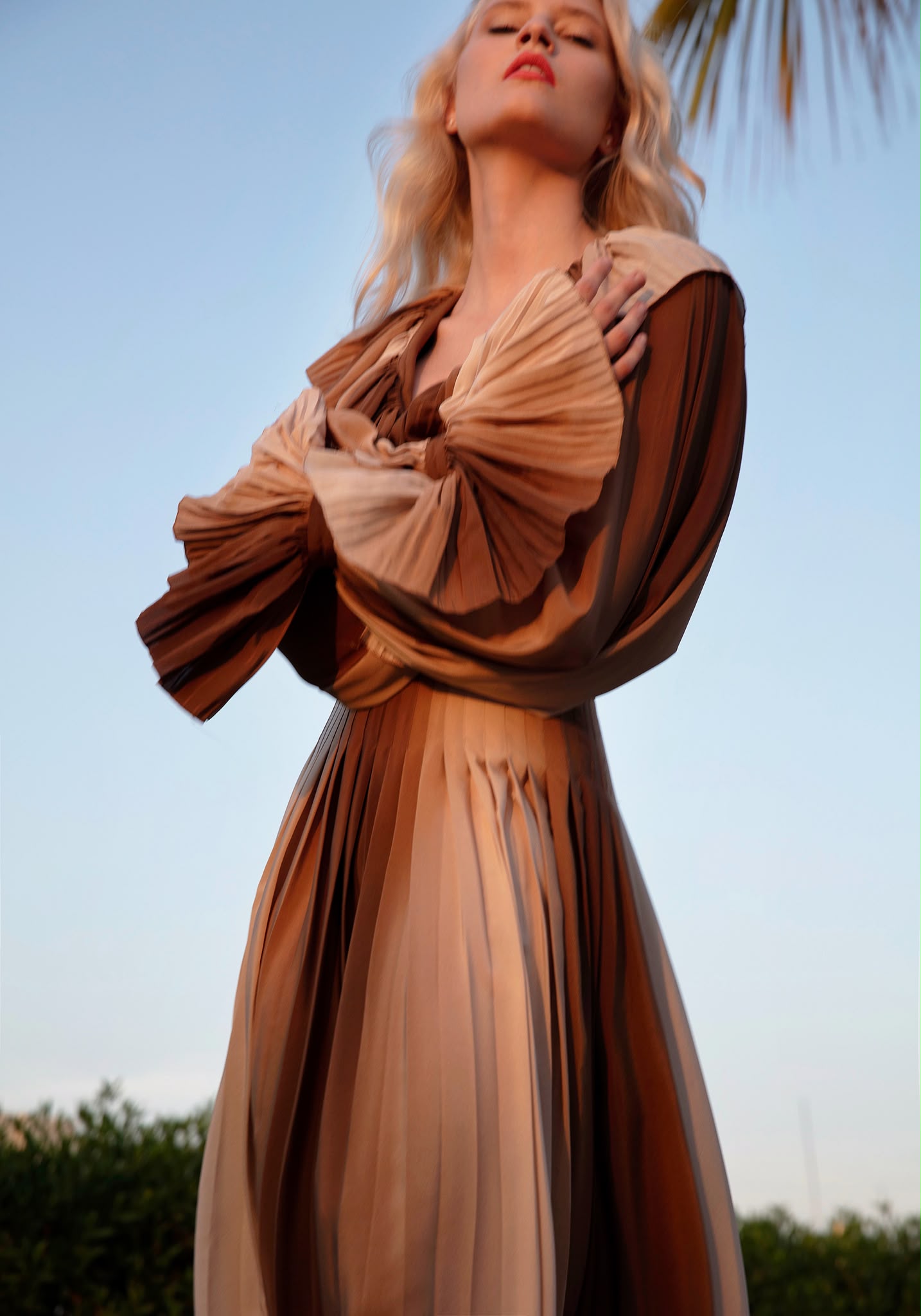 Ana Schurmann for Harper's Bazaar Turkey, shot by Mehmet Erzincan — pleated ombré gown photographed from below at dusk